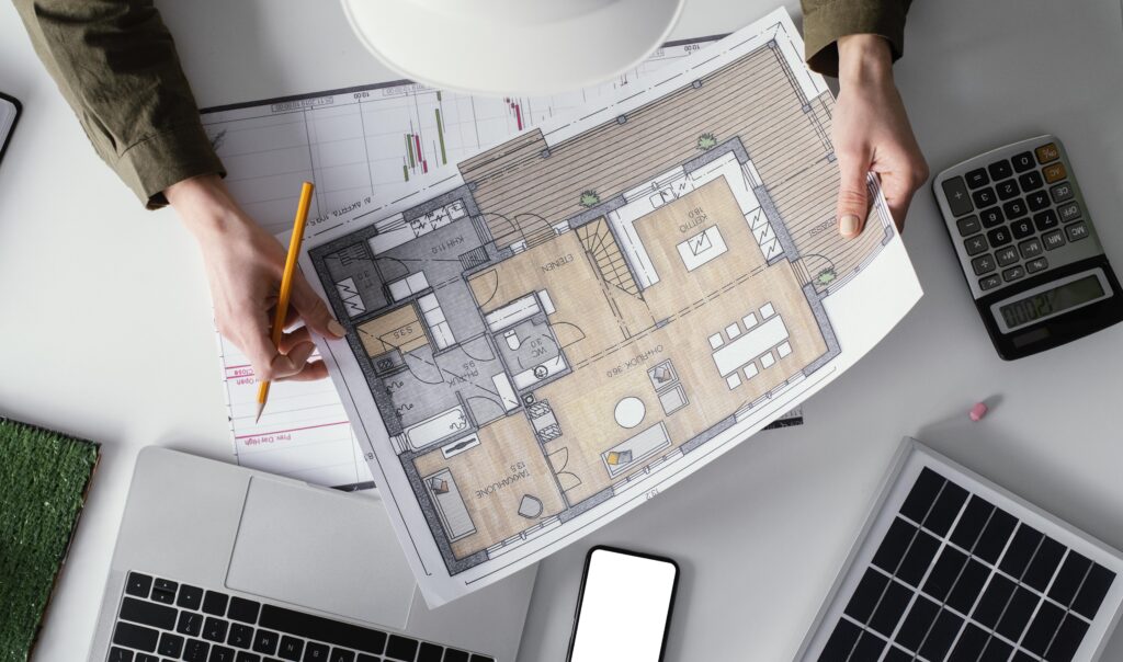 Calculator, house plans and euro notes on a wooden table symbolising renovation budgeting in France